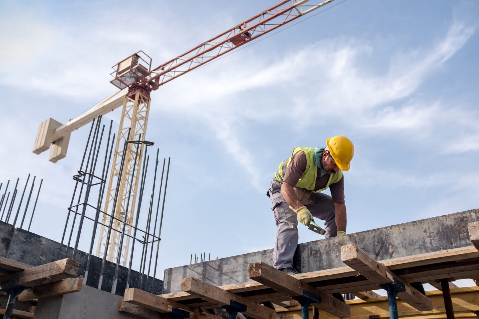Construction worker on building site with crane.