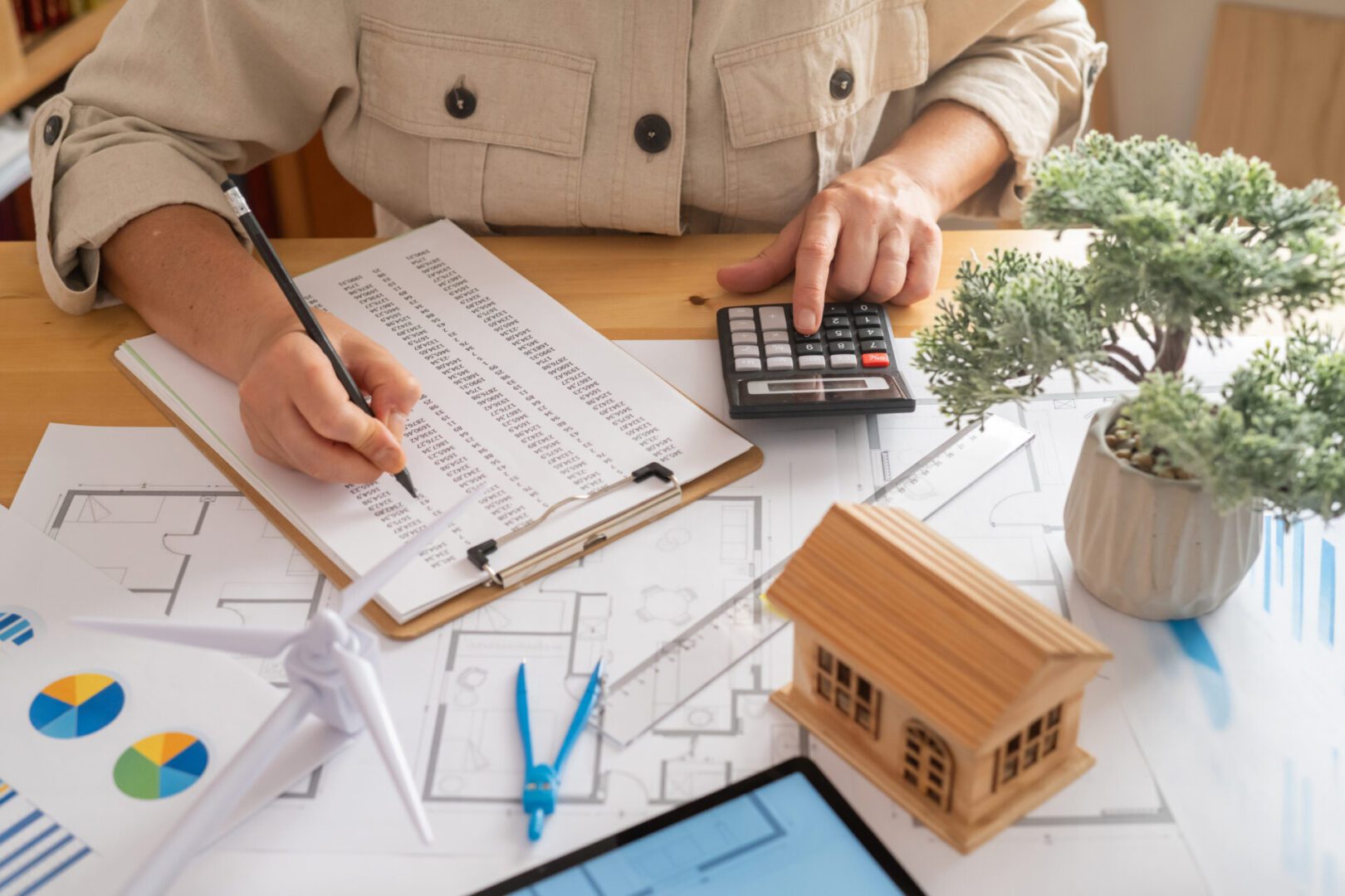 Person calculating with blueprints and calculator.