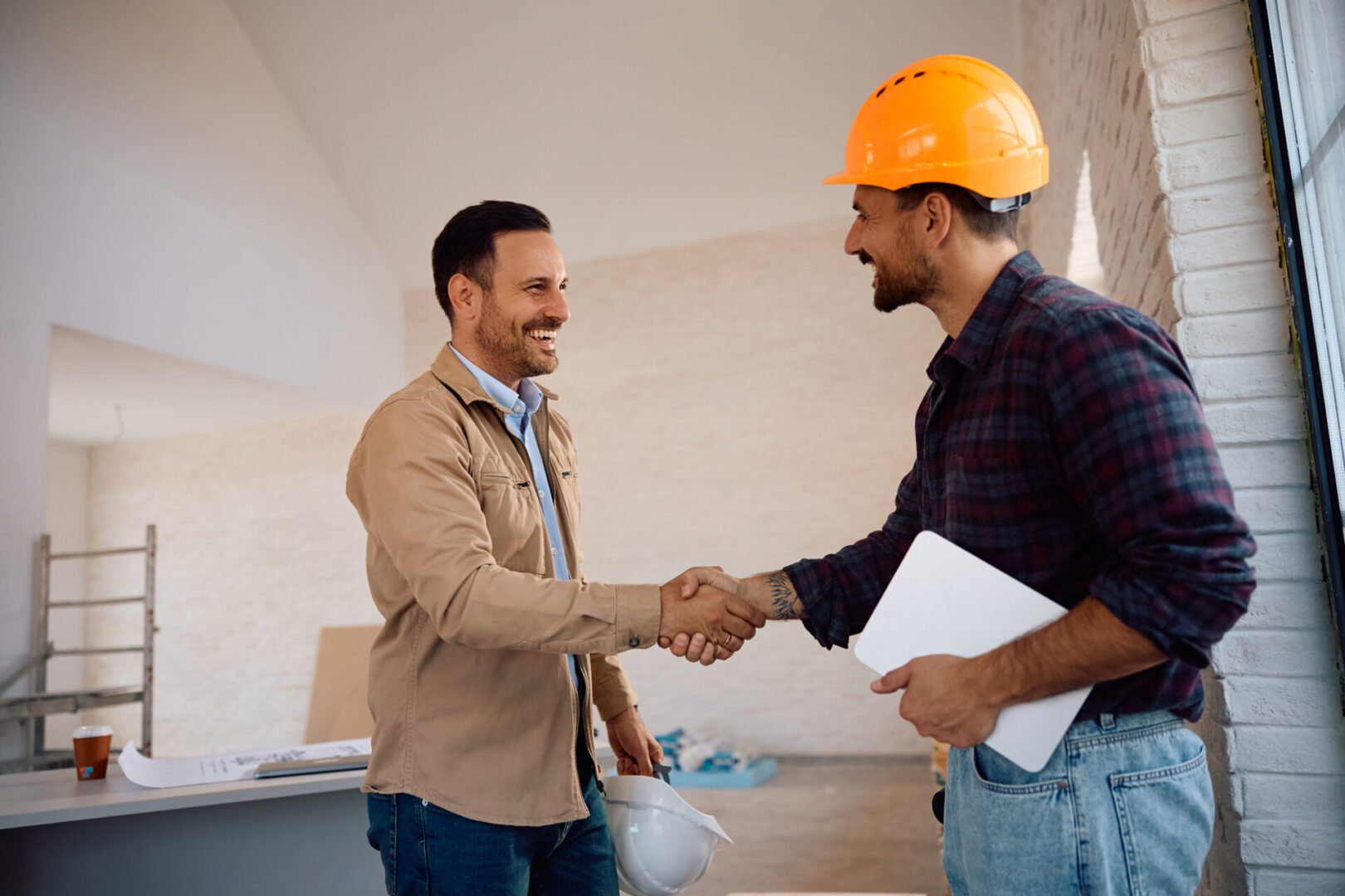 Two men shaking hands at construction site.
