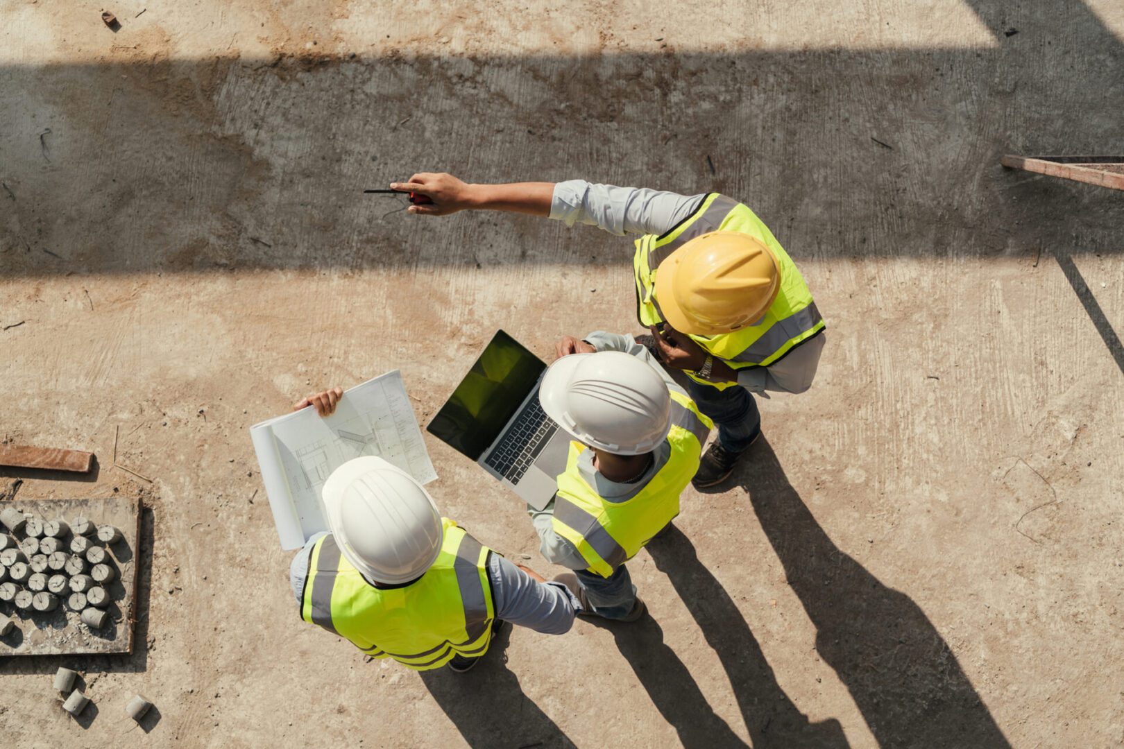 Construction workers reviewing plans and laptop.