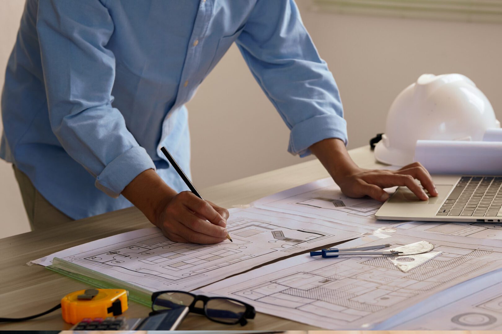 Architect working on building plans at desk.